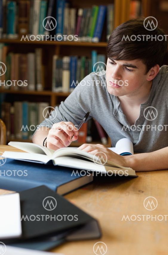 Portrait of a handsome student writing a paper