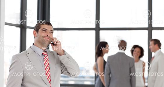Businessman holding a phone at workplace with his colleagues