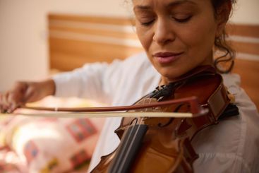 Woman playing violin with concentration and passion in...