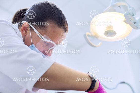 Experienced dentist treats teeth in patient, care and...