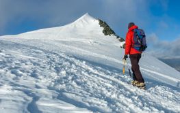 Mountaineer climbs a snowy peak in swiss Alps.