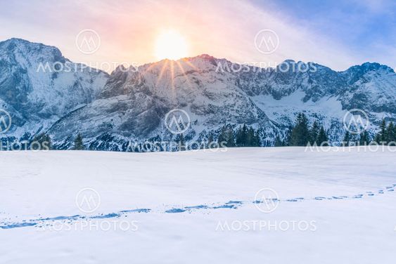 Sun shining over mountain peaks and snow