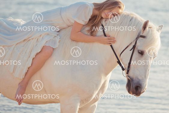 Girl in white dress with horse on the beach