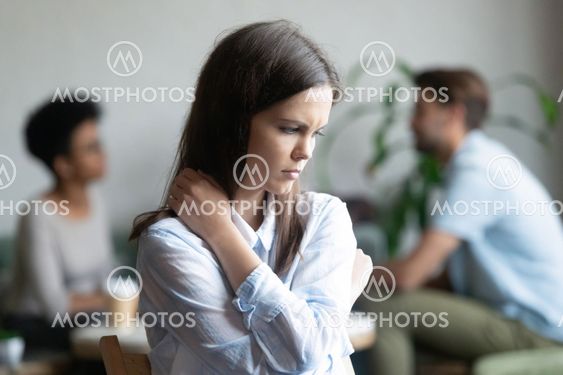 Upset young woman sitting alone in cafe offended at friends
