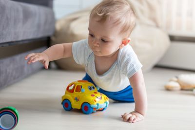 Portrait of cute baby boy crawling on floor and playing...