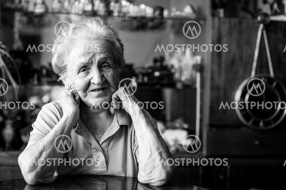 Portrait of an elderly woman at the table in the house.
