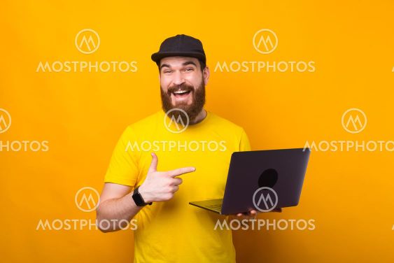 Charming bearded hipster man pointing at his new laptop...