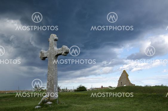 Historic cross and chapel ruin in stormy weather