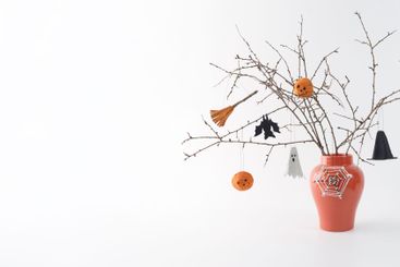 Dry branches with Halloween ornaments in orange vase....