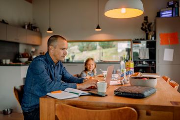 Focused businessman working on laptop while sitting near...