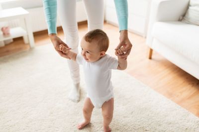 happy baby learning to walk with mother help