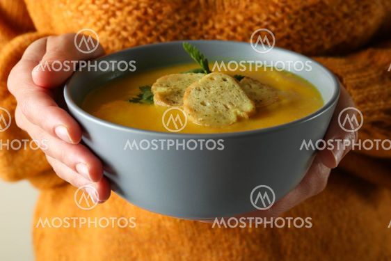 Woman holds bowl of pumpkin soup, close up