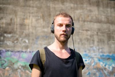 hipster modern stylish blonde man listening music in park