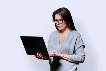 Serious middle aged woman using laptop on white background