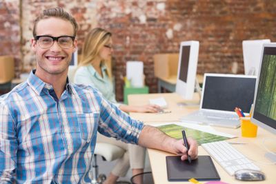 Happy male photo editor using computer in office