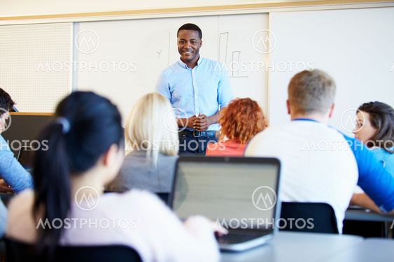 Male Tutor Teaching University Students In Classroom