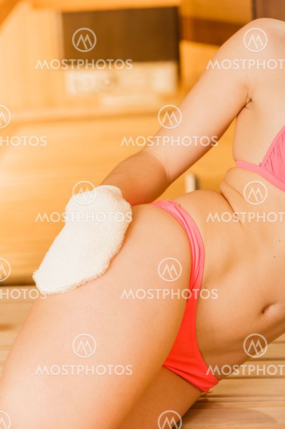 Closeup of woman in sauna with exfoliating glove.