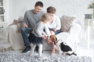 happy parents looking at their daughter, who feeds the dog