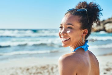 Happy, beach and woman by ocean with smile for vacation,...