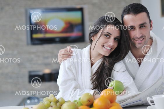Happy couple reading the newspaper in the kitchen at breakfast