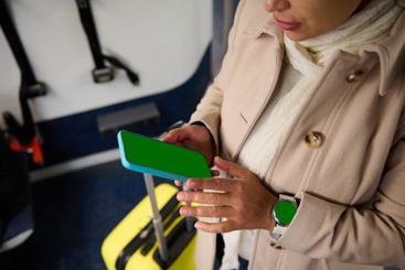 Traveler using mobile phone on train with luggage in...