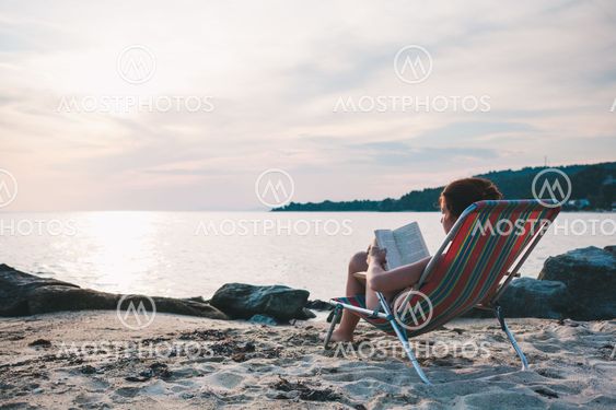 Young woman reading a book on the beach