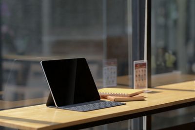 Cropped shot of digital tablet and notebook on wooden desk