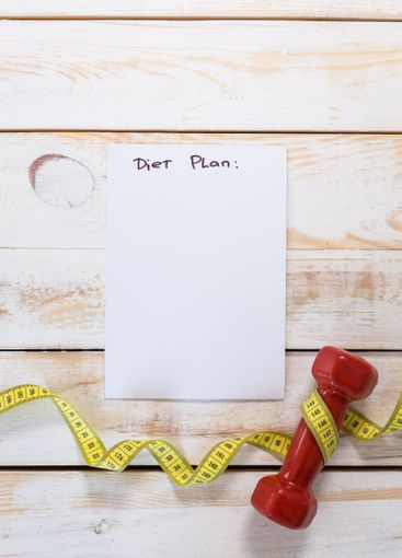 Fitness concept with dumbbells and measuring tape