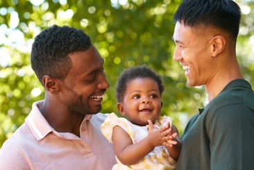 Loving Same Sex Male Couple Or Friends Cuddling Baby...