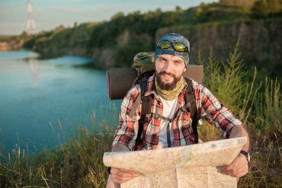 Young caucasian man with backpack sitting on the top of...