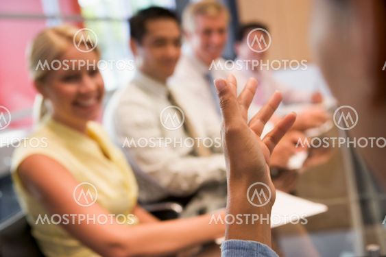 Five businesspeople at boardroom table with focus on...