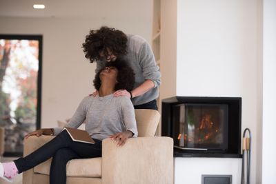 multiethnic couple hugging in front of fireplace