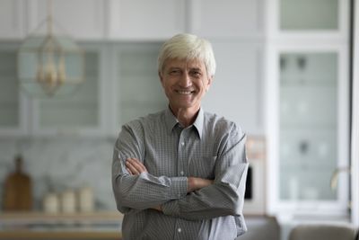 Retired man standing in fashionable domestic kitchen...