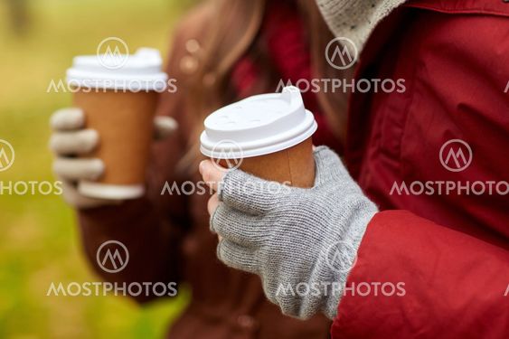 close up of couple hands with coffee in autumn