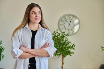 Confident young woman with crossed arms in home interior