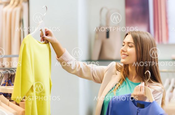 happy young woman choosing clothes in mall