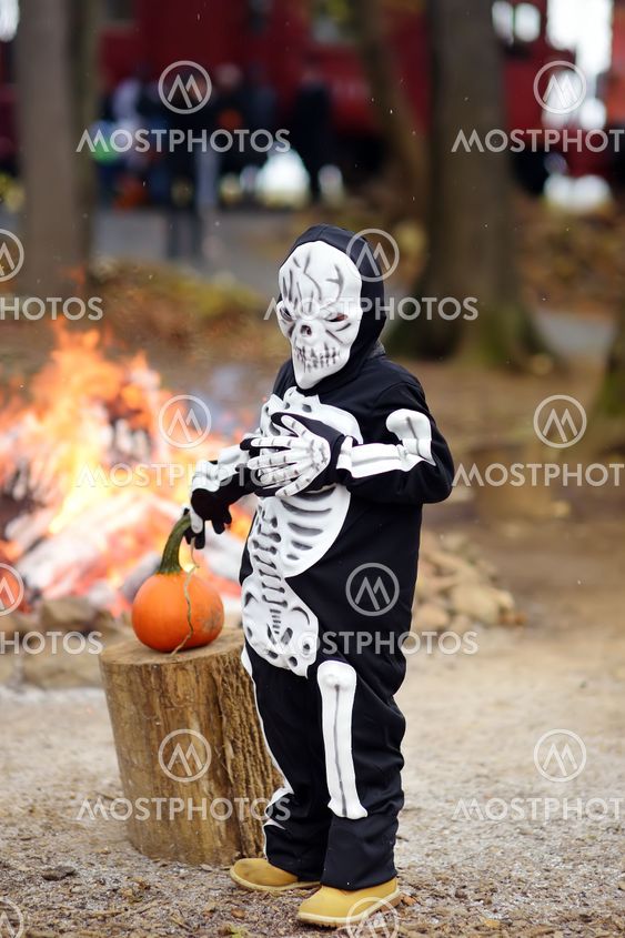 Little boy in scary skeleton costume on background of...