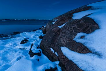 Winter evening at the rocky shoreline featuring snow and...
