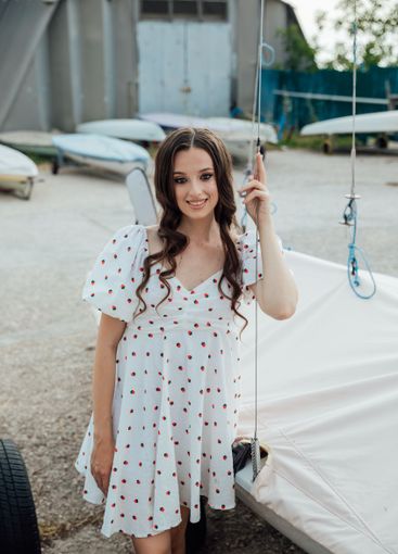 woman in summer dress sitting by sailboats in yacht club