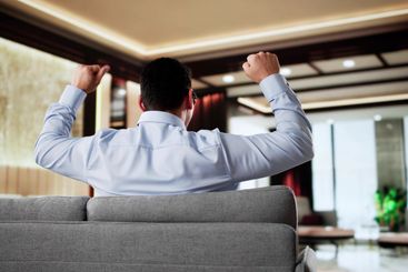 Happy Man Sitting On Sofa Thinking