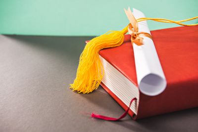 close up of books, diploma and tassel of graduation cap...