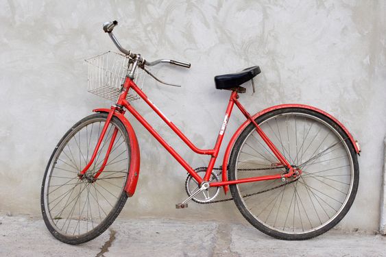 old red bicycle leaning against a wall