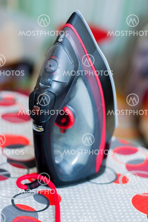 Iron stands on the ironing board closeup