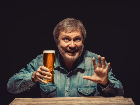 The smiling man in denim shirt with glass of beer