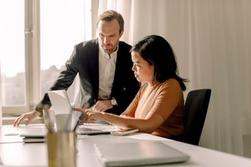 Businesswoman with businessman discussing over laptop in...
