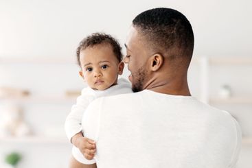 Black Millennial Man With Adorable Baby Boy In Hands...
