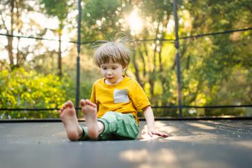 Little boy jumping on a trampoline in a backyard on warm...