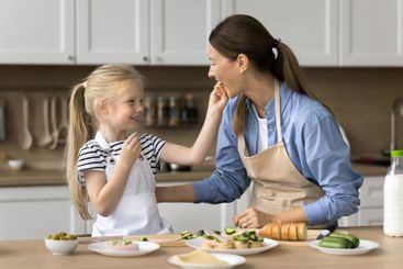 Cute little child feeding small snack to lovely mom