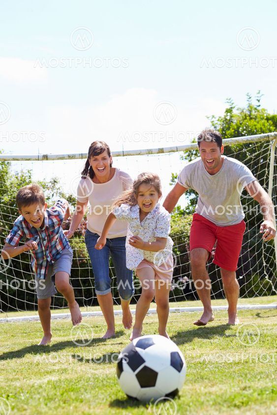 Family Playing Football In Garden Together
