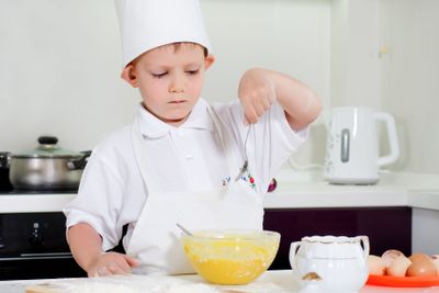 Young boy chef adding ingredients to his bowl